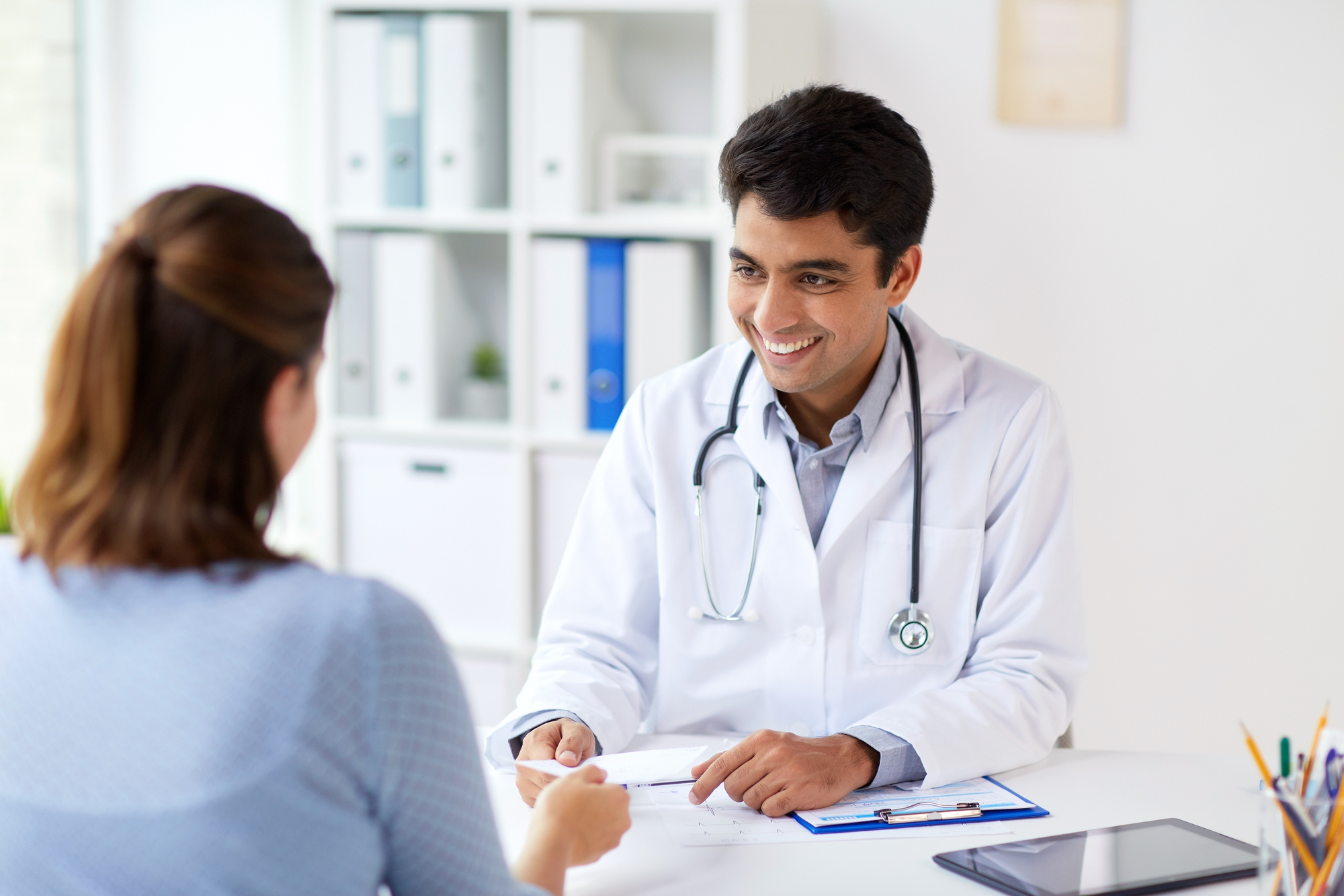 Smiling Doctor Giving Medical File To Patient